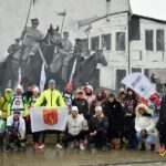Wspólna fotografia biegaczy i mieszkańców Strzałkowa na tle muralu upamiętniającego Powstanie Wielkopolskie