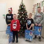 Czterech chłopców ze świątecznymi paczkami przy choince