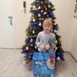 Dziewczynka z torbą świąteczną na tle przystrojonej choinki