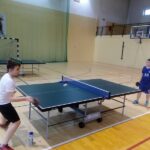 Dwóch chłopców w hali sportowej grających w tenisa stołowego