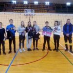 Grupa młodzieży w hali sportowej z nagrodami po turnieju siatkówki