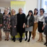 Osiem kobiet - nowy zarząd stowarzyszenia pozuje do zdjęcia na tle baneru stowarzyszenia