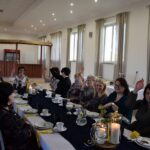 Kilkanaście kobiet siedzi za zastawionym stołem