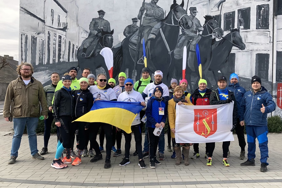 Grupa osób z flagami Ukrainy i Gminy Strzałkowo, w tle mural upamiętniający Powstanie Wielkopolskie