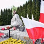 Pomnik Powstańców Wielkopolskich, obok biało-czerwone flagi