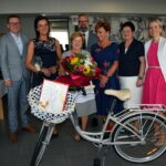 Lidia Śmidowicz z kierownikami i dyrektorami gminnych jednostek organizacyjnych oraz prezentem w postaci roweru