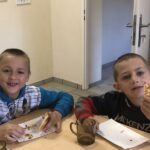 Dwóch chłopców siedzi przy stole jedząc pizzę
