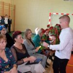 Uczeń ZSP w Wólce wręcza róże nauczycielom i gościom zaproszonym na uroczystość