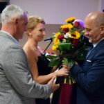 Przedstawicielka par małżeńskich wręcza wójtowi bukiet kwiatów