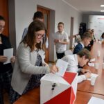 Głosowanie na przewodniczącego rady. Jedna z radnych wrzuca złożoną kartkę papieru do biało-czerwonej urny