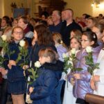 Dziewczynki ze scholi parafialnej w Strzałkowie z białymi różami w rękach. Na drugim planie wierni witający Matkę Bożą