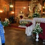 Proboszcz parafii w Ostrowie Kościelnym stoi przed obrazem Matki Bożej z bukietem kwiatów