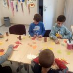Sześciu chłopców podczas przygotowywania prac z kolorowych kartek w kształcie liści