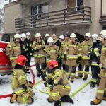 Grupa strażaków stoi przed domem, w którym odbywają się ćwiczenia