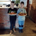 Dwóch chłopców prezentuje wykonane przez siebie pizze
