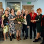 Kilkuosobowa grupa kobiet z wazonem róż pozuje do zdjęcia
