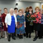 Kilka kobiet z wazonem róż pozuje do zdjęcia