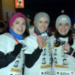 Trzy młode kobiety uśmiechają się do obiektywu pokazując medale
