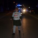 Kobieta z kijkami wchodzi na metę, za nią oświetlony wóz strażacki zamykający bieg