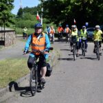 Kilkunastoosobowa grupa rowerzystów dojeżdża do przystanku w Graboszewie