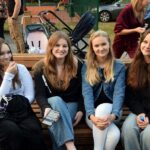 Cztery uśmiechnięte młode dziewczyny siedzą na ławce