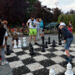 Kilka osób gra w szachy na wielkiej szachownicy