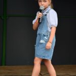 Dziewczynka przechadza się po scenie śpiewając do mikrofonu