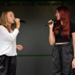 Dwie nastolatki na scenie śpiewają do mikrofonu