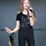 Młoda dziewczyna śpiewa do mikrofonu na scenie