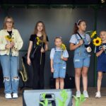 Pięć wokalistek Studia Piosenki stoi na scenie ze słonecznikami w rękach