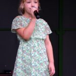 Dziewczynka na scenie śpiewa do mikrofonu