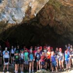 Kilkudziesięcioosobowa grupa uczestników u wejścia do jaskini