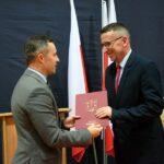 Zastępca wójta wręcza dyrektorowi ZSP w Wólce teczkę z herbem gminy