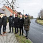 Przedstawiciele władz Powiatu Słupeckiego i Gminy Strzałkowo stoją na chodniku i pozują do zdjęcia przy wyremontowanej drodze