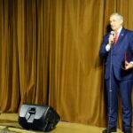 Wiceminister Wiesław Szczepański stoi na skraju sceny i przemawia do mikrofonu na tle zasłoniętej kurtyny