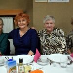 Cztery uśmiechnięte kobiety siedzą przy stole
