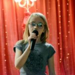 Dziewczynka na scenie śpiewa do mikrofonu