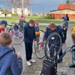 Kilka osób na rowerach przygląda się policjantce, która przygotowuje rower do znakowania