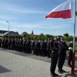 Strażak z pocztu flagowego wciąga biało-czerwoną flagę na maszt