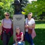 Trzy uczestniczki wycieczki pozują do zdjęcia przy pomniku z popiersiem Czesława Niemena