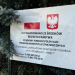 Tablica informacyjna z flagą Polski i Godłem oraz informacjami na temat inwestycji i pozyskanego dofinansowania