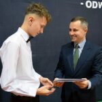 Wójt wręcza stypendyście z ZSP Wólka dyplom w teczce