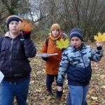 Trzech chłopców, każdy z nich w ręku trzyma liść