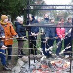 Uczniowie przy ognisku pieką zawinięte na kije kawałki ciasta