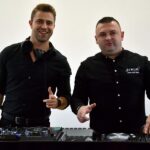 Dwóch DJ-ów prowadzących imprezę pozuje do zdjęcia